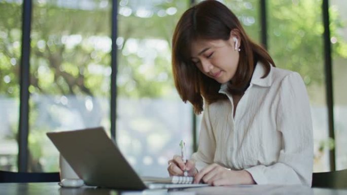 女商人在使用笔记本电脑时写笔记