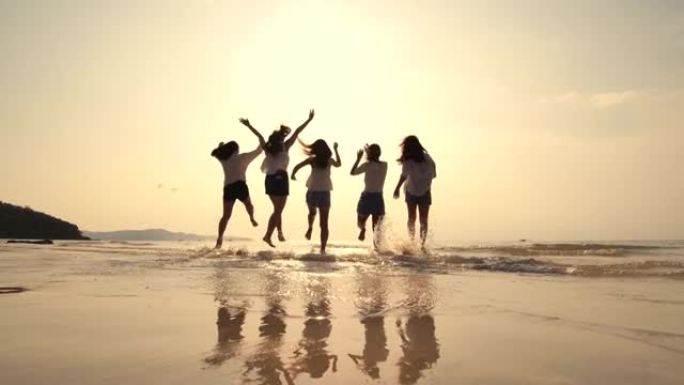 一群朋友在日落时带着快乐的情感在沙滩上奔跑