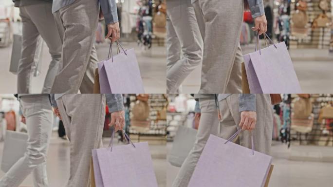 夫妇带着购物袋沿着服装店散步