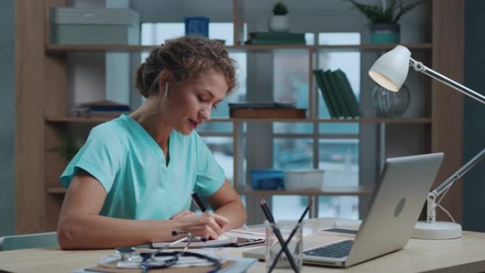 医生女在网上诊所的笔记本电脑上与病人视频通话。女医师在视频会议上咨询远程人员。聪明的护士晚上在室内讨