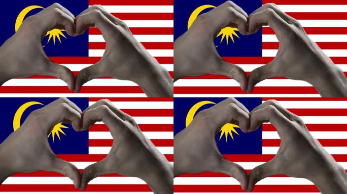 双手在马来西亚国旗上显示心脏标志。