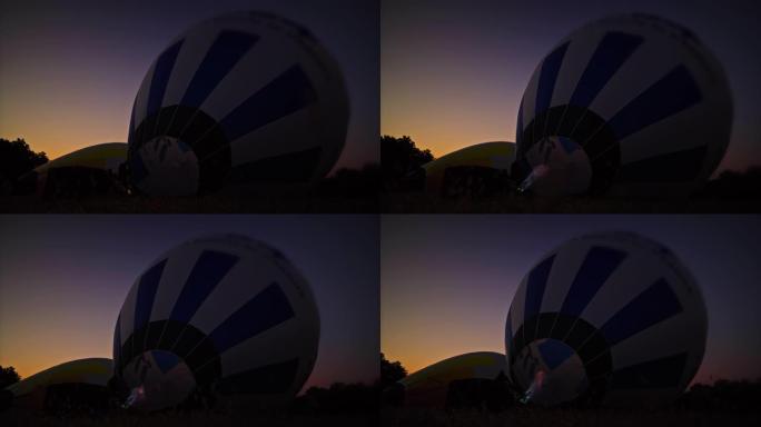 黎明时分，丙烷火焰在黑暗的田野中膨胀热气球
