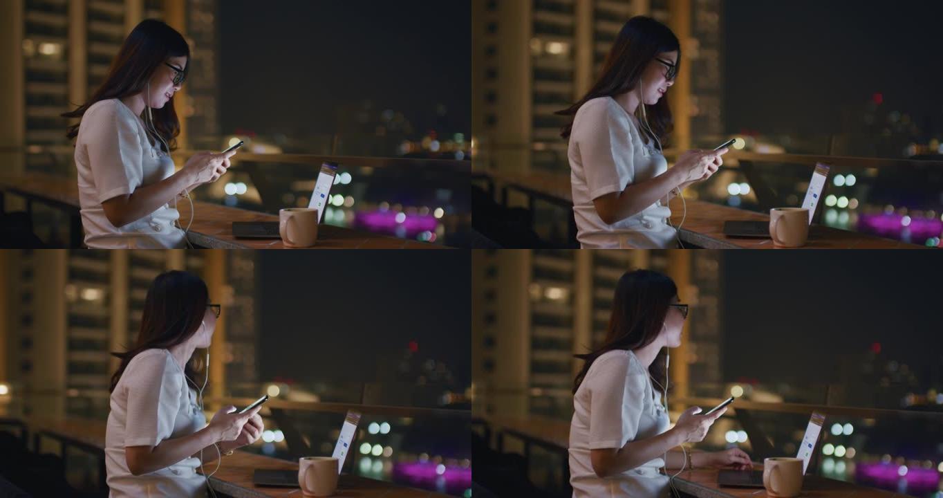 美丽的亚洲女人使用智能手机享受音乐在晚上