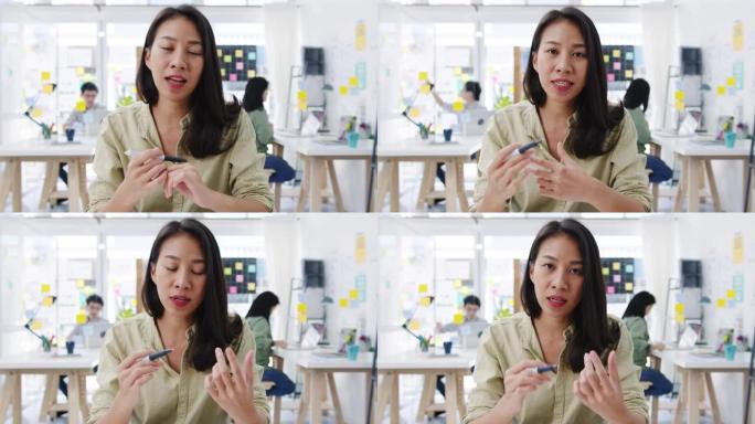亚洲女商人在新的正常情况下进行社交距离预防病毒在办公室工作时向朋友介绍有关视频通话计划的摄像机演示。