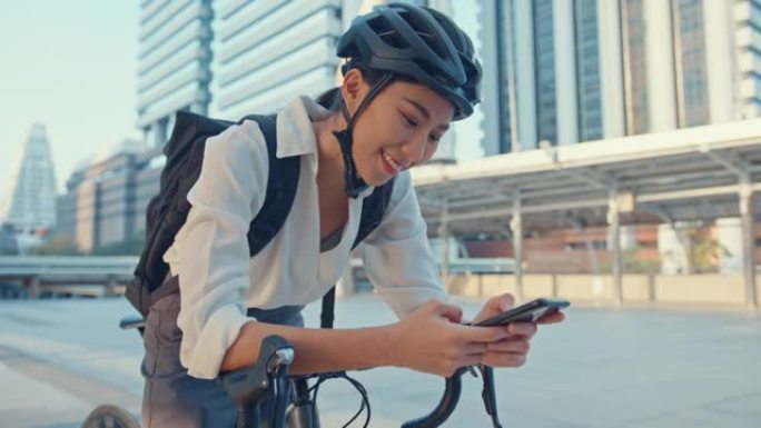 带着背包微笑的亚洲女商人在城市站在街上骑自行车去办公室上班。