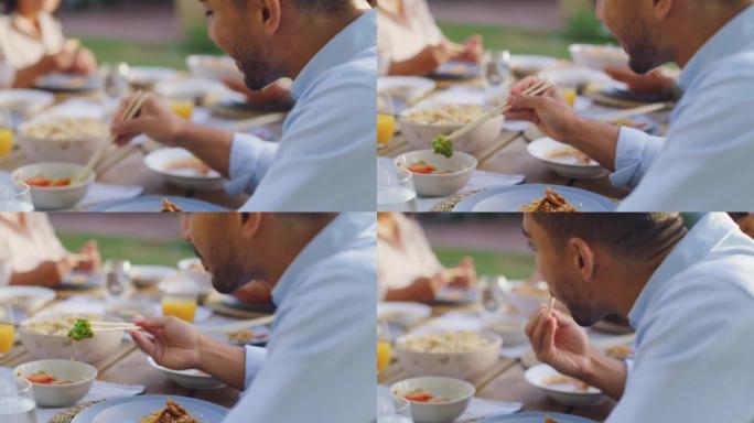 一个亚洲人用筷子和家人一起吃饭。
年轻人在活动场所吃午餐或晚餐，或在户外用餐区聚会。一起分享健康美味