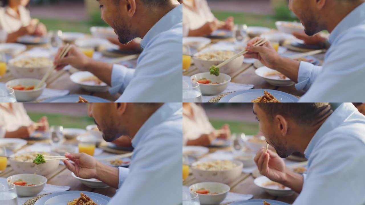 一个亚洲人用筷子和家人一起吃饭。
年轻人在活动场所吃午餐或晚餐，或在户外用餐区聚会。一起分享健康美味