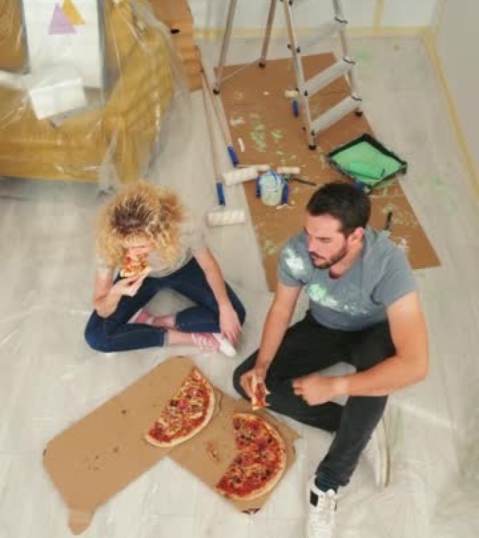 开朗的年轻夫妇在家享受披萨。