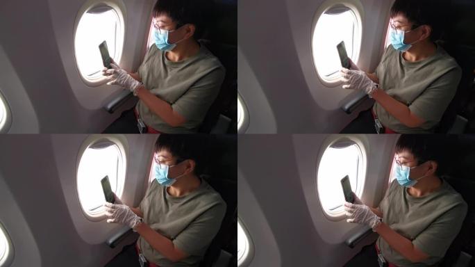 一名亚裔中国中年妇女在商业飞机的乘客座位上，戴着口罩和橡胶手术手套望着窗外