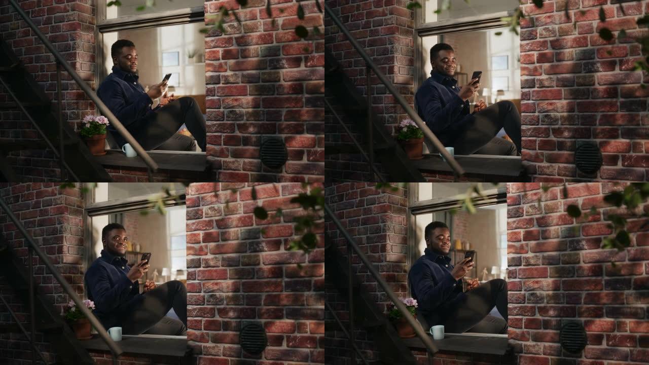 黑人帅哥一边用智能手机欣赏卧室窗户的景色。年轻男性在布鲁克林风格的褐砂石屋喝咖啡和放松时检查社交媒体