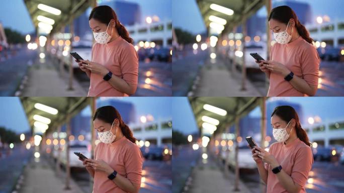 亚洲女子晚上戴口罩使用智能手机