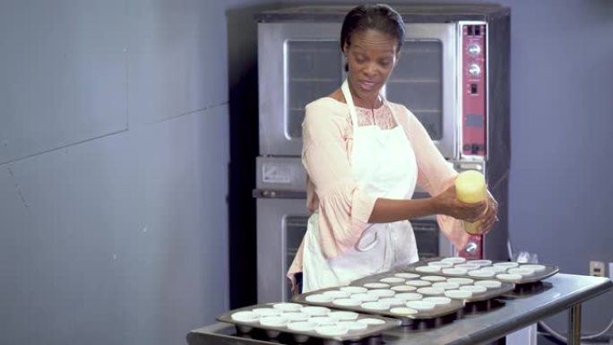 在面包店工作的非裔美国妇女制作纸杯蛋糕