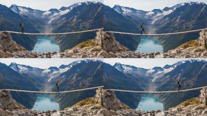女徒步旅行者在山涧上的吊桥上行走，欣赏山谷湖和周围山脉的壮丽景色