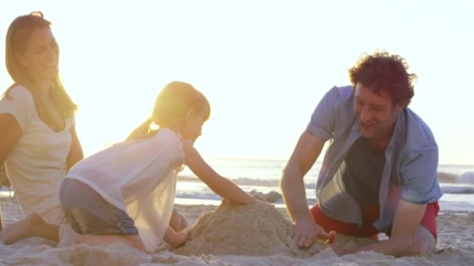 一个小女孩和她的父母在海滩上一起建造沙堡的4k视频片段