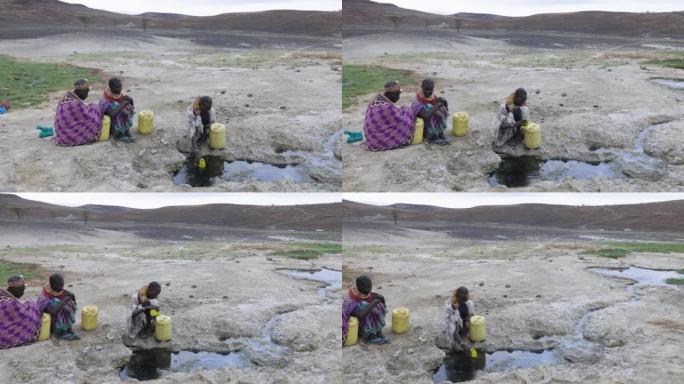 气候变化，干旱，水危机。平移特写视图。非洲妇女从肯尼亚图尔卡纳地区的火山泉水中收集塑料容器中的水