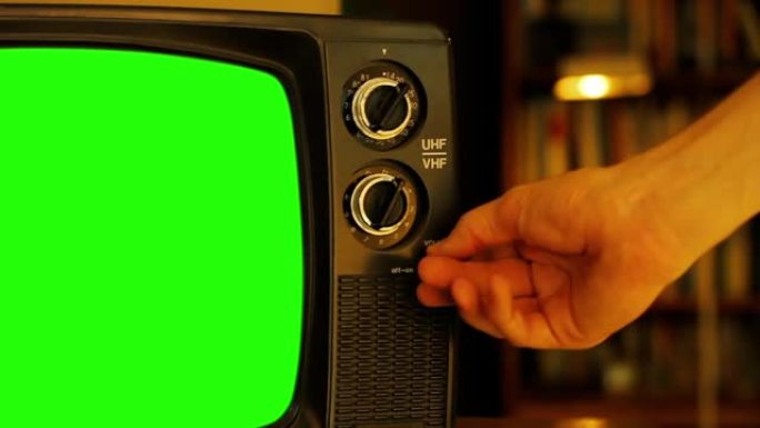 男人把手放在绿屏的旧电视上。特写。