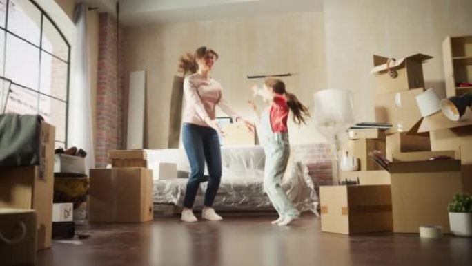 真正快乐的母女俩搬进了他们舒适的新家。开朗的年轻家庭，女孩在公寓中间玩得开心，跳舞，拥抱。客厅有未包