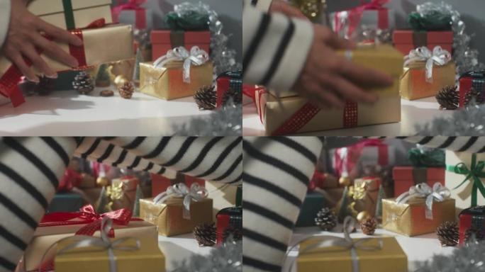 女孩手的特写准备礼物盒冬季圣诞装饰品在桌子上。