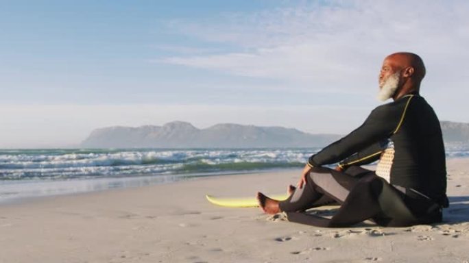 资深非裔美国男子坐在沙滩上冲浪板