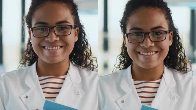 垂直屏幕截图。医学科学实验室: 美丽聪明的年轻黑人科学家的肖像，穿着白大褂和眼镜，拿着测试书，微笑着