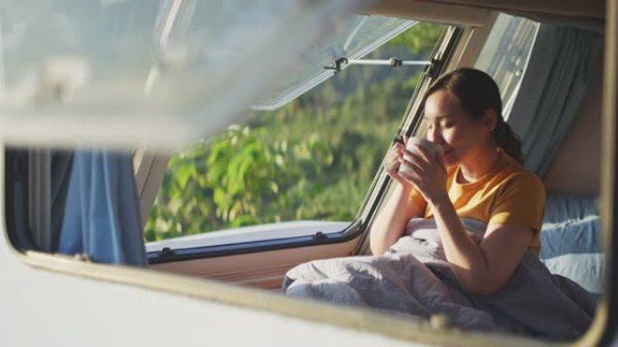 女人在露营车上看着山喝茶