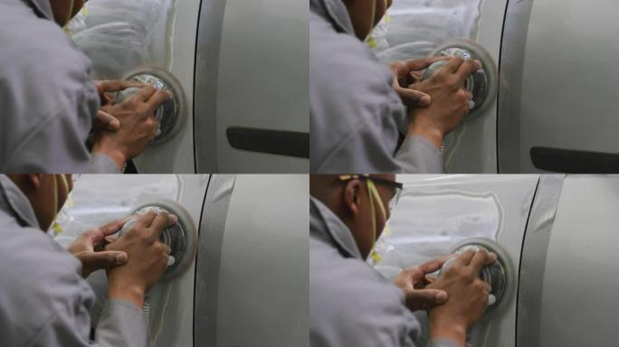非裔美国男汽车修理工戴口罩用研磨机打磨汽车侧面