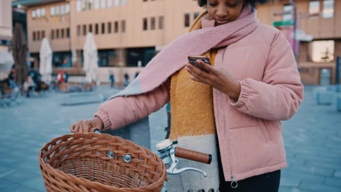 年轻女子在城市人行道上骑自行车时使用手机
