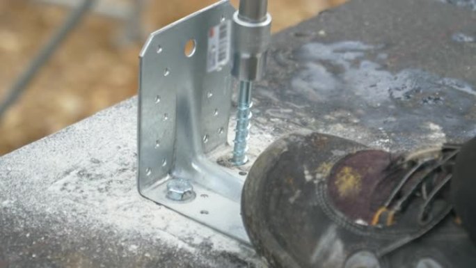 特写: Builder使用电钻将螺栓固定到混凝土地基上。