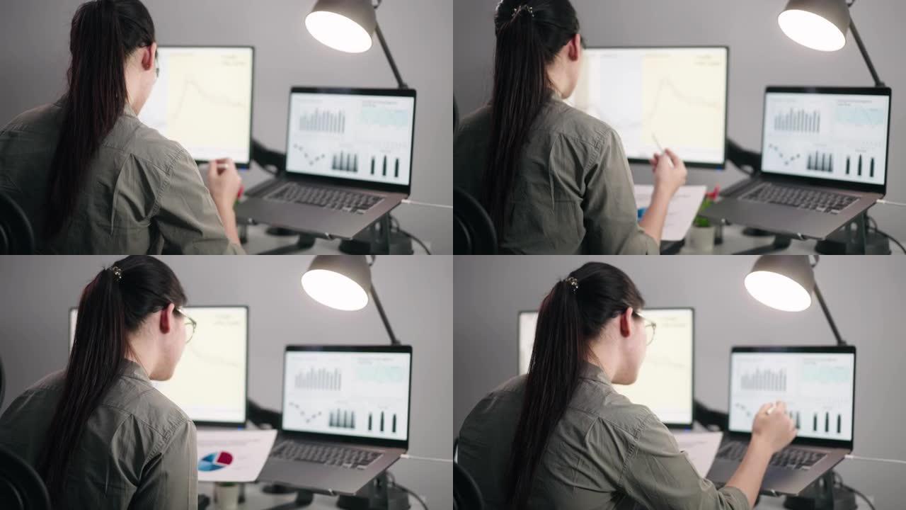 在一个被数据电脑屏幕包围的办公室里工作的亚洲女商人