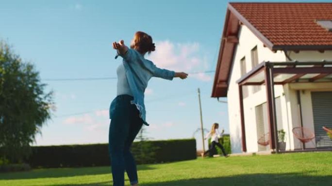 SLO MO欣喜若狂的女人在小房子的绿色草坪上奔跑时旋转