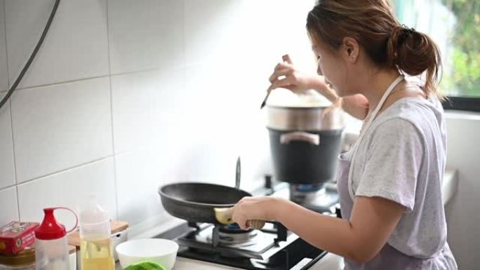 一位亚洲中国美女在厨房里煎鸡蛋准备吃早餐