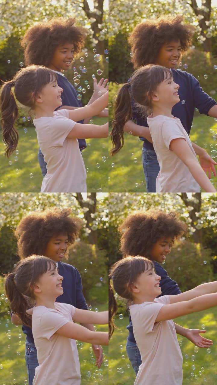微笑的男孩和女孩在户外玩花园泡泡的垂直视频 -- 慢动作拍摄