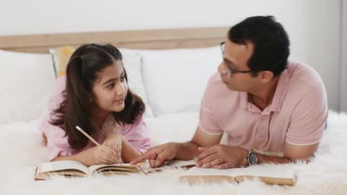 年轻的父亲解释家庭作业帮助女童学习