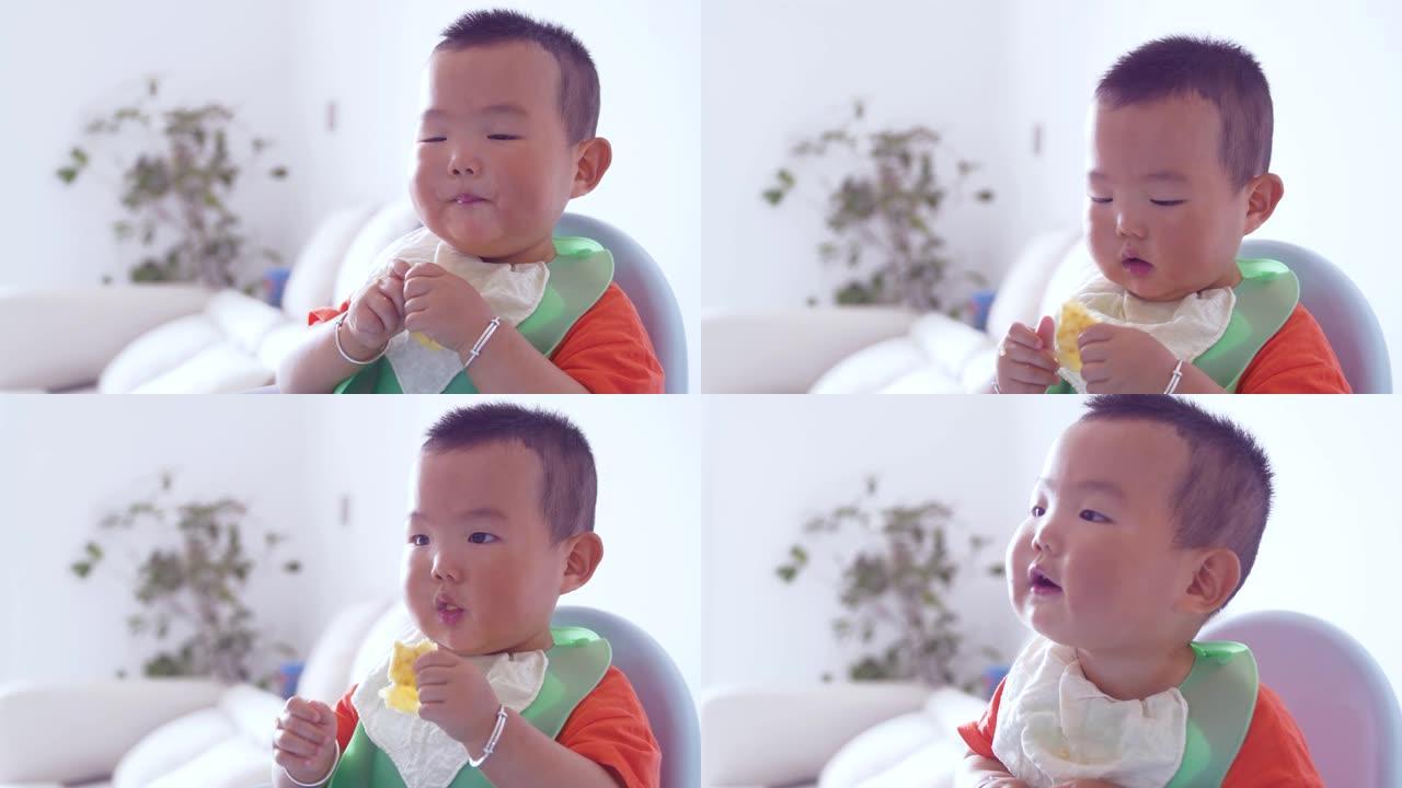 男婴坐在高脚椅上吃食物