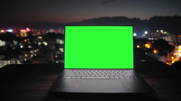 绿屏笔记本电脑与城市夜背景