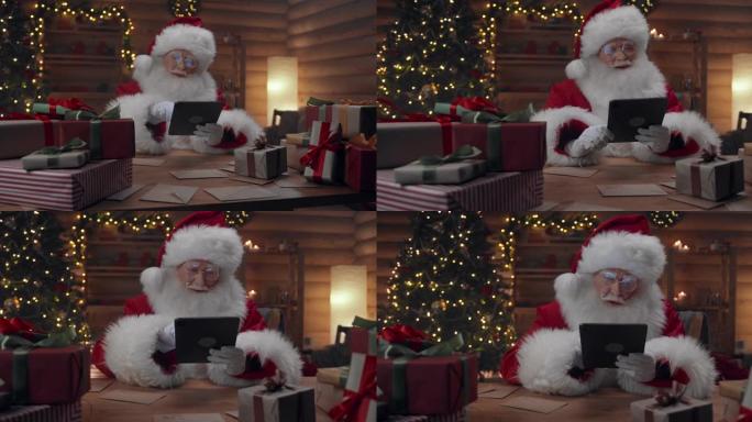 圣诞老人坐在圣诞节装饰的办公室里在他的垫子上在线购物