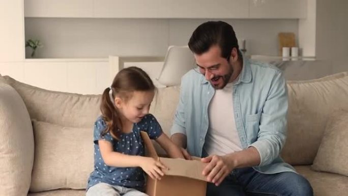 小女孩和爸爸用礼物打开包裹感到幸福