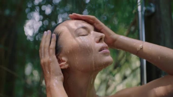 性感的女人在淋浴穿着比基尼洗身体清洁皮肤与清爽的水享受自然美容温泉在大自然的户外淋浴