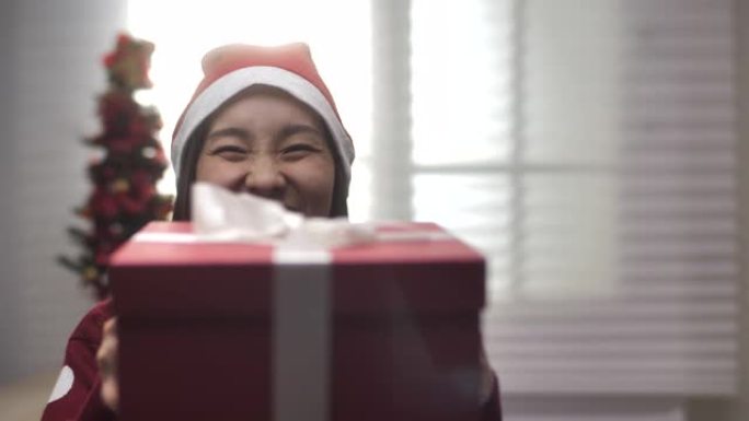 亚洲女人指着圣诞礼盒，手里拿着和展示礼盒