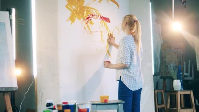 金发女人正在用手在一块巨大的画布上画画