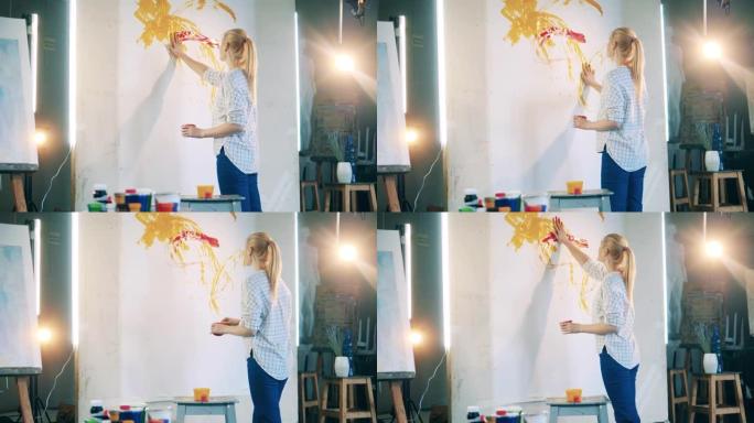 金发女人正在用手在一块巨大的画布上画画