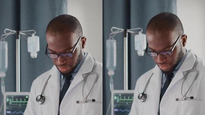 垂直屏幕。医院病房: 戴眼镜的英俊黑人医生使用数字平板电脑，检查患者的病史，最新医学研究。设备先进的