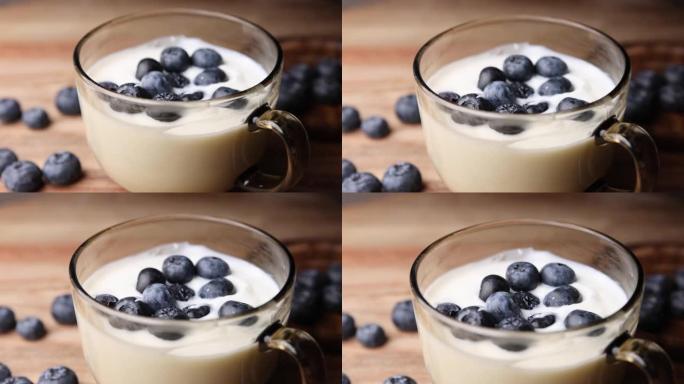 新鲜酸奶和蓝色浆果放在桌子上的玻璃碗中