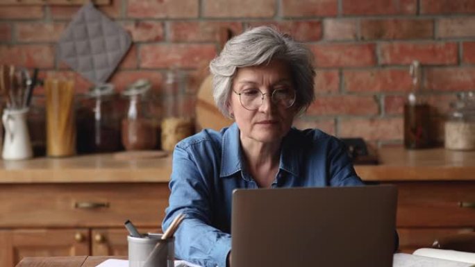 年长的女人使用笔记本电脑阅读好消息感到喜出望外