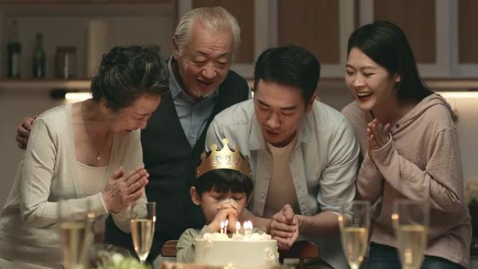 亚洲小男孩在生日聚会上许愿并吹蜡烛