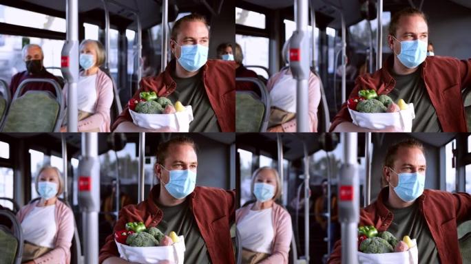 戴着covid面具的男子坐在公共汽车里，拿着购物袋