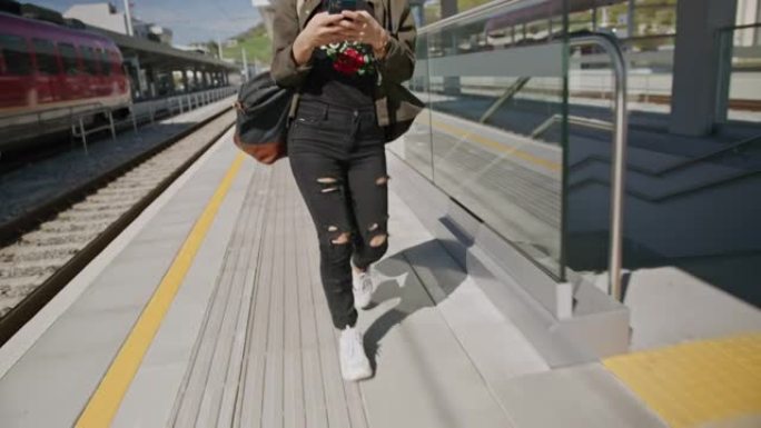 女人在铁路平台上行走时使用手机