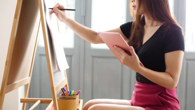 手拿着数字平板电脑素描的艺术家女性肖像