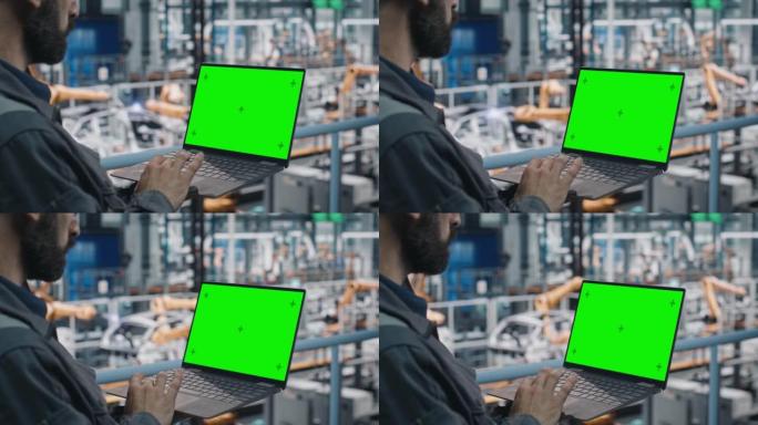 汽车工厂工程师在工作制服中使用带有绿屏模型显示的笔记本电脑。在专门用于车辆生产的汽车工业制造工厂使用