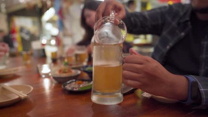 亚洲男子在日本餐厅为同事倒啤酒